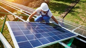 Professional worker installing solar panels on the green metal construction, using different equipment, wearing helmet. Innovative solution for energy solving. Use renewable resources. Green energy.