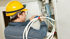 One electrician builder at work installing energy saving meter into electric line distribution fuseboard